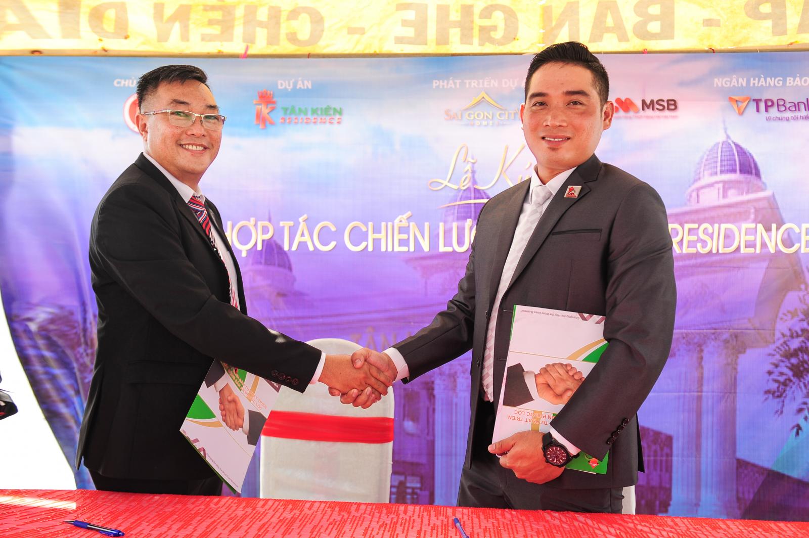 Hai người đàn ông mặc vest cười và bắt tay nhau