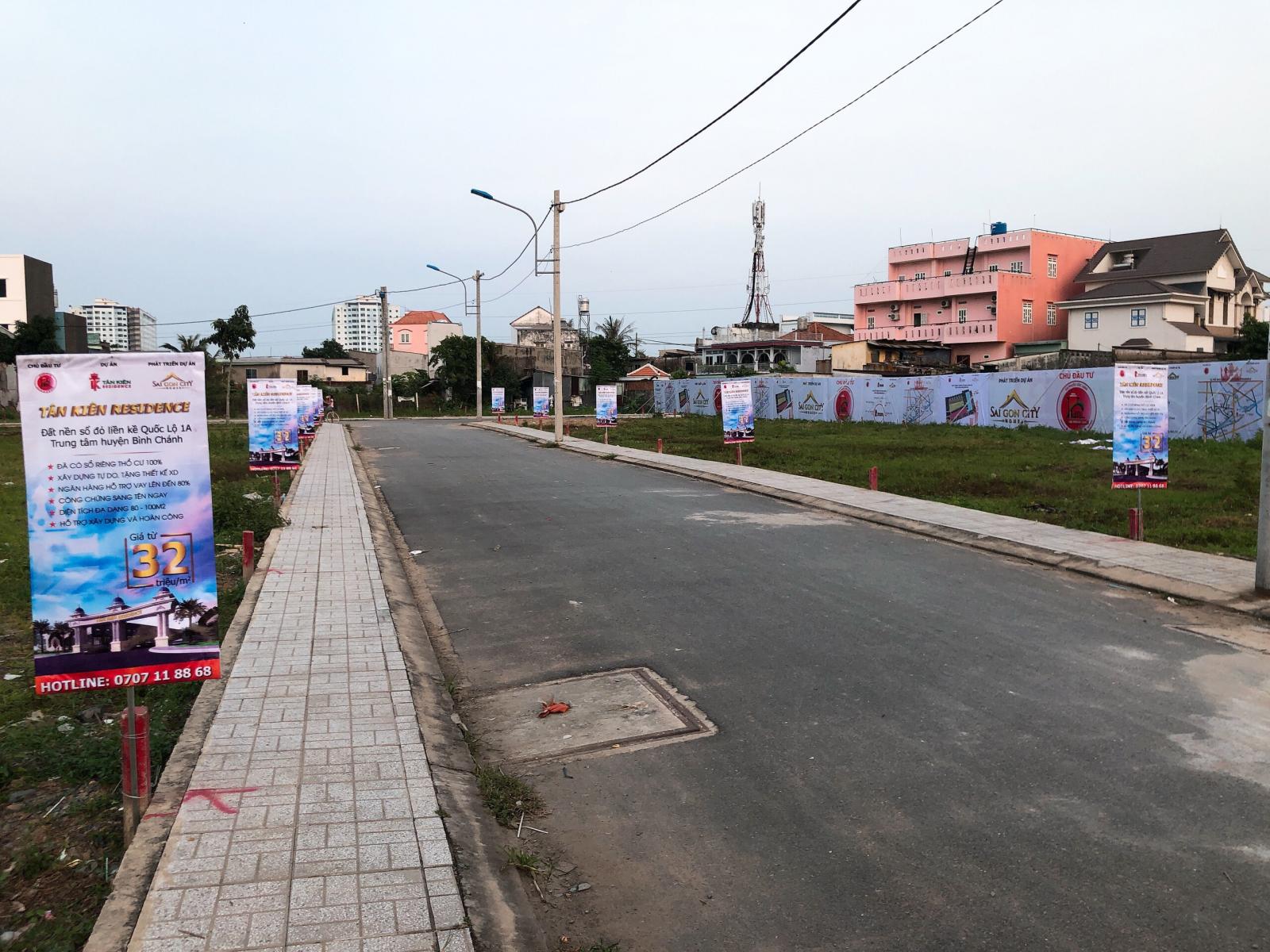 Ảnh chụp một con đường, hai bên có cắm các bảng quảng cáo dự án