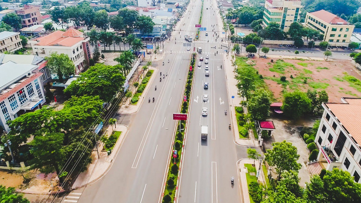 Hình ảnh con đường gồm 2 làn xe có xe cộ đang chạy và nhà hai bên đường