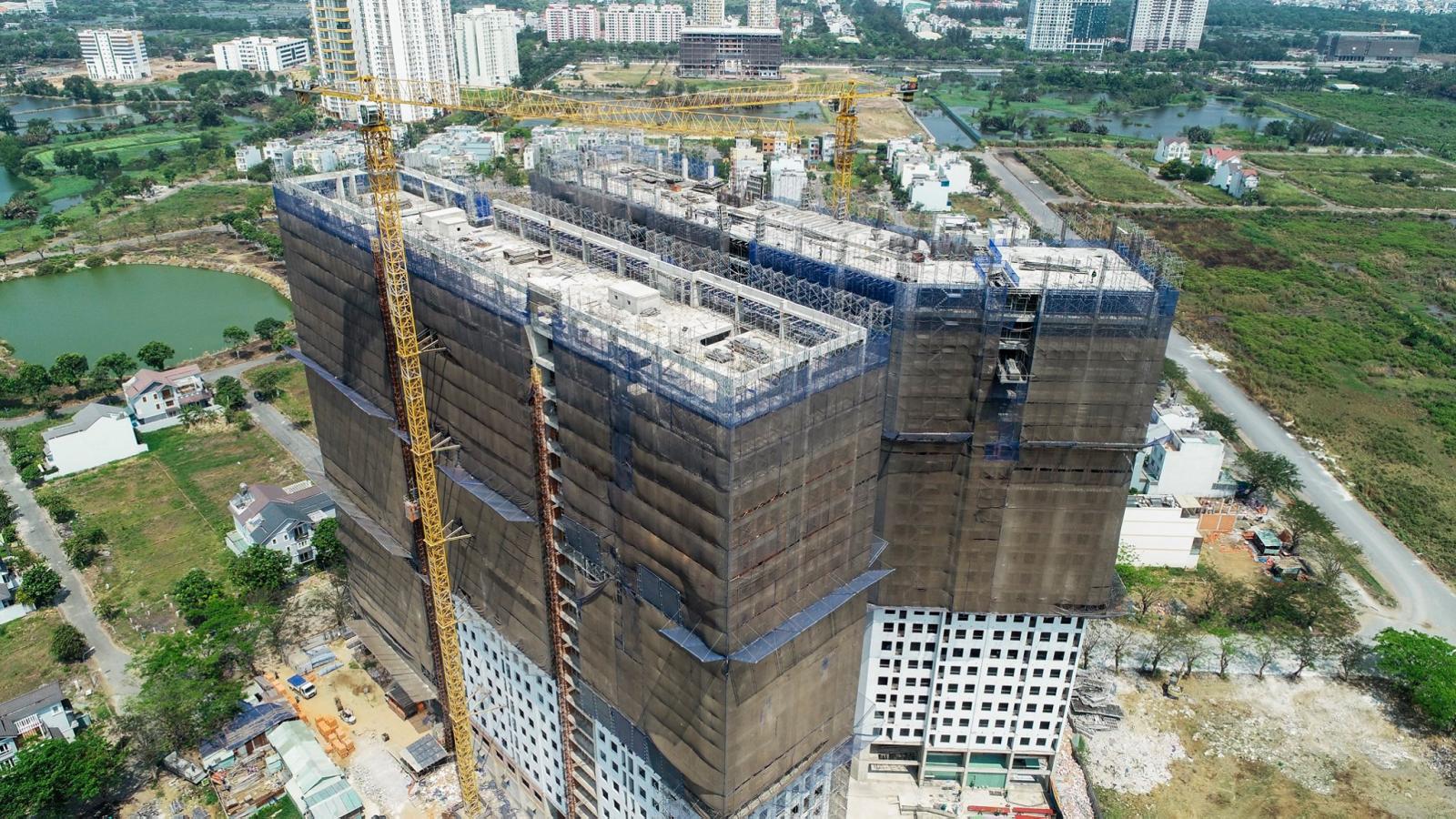 Tòa chung cư cao tầng đang xây dựng, bọc lưới bảo vệ màu xám bên ngoài.