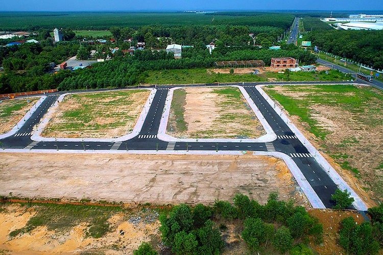 một khu đất trống được chia thành nhiều lô diện tích khác nhau, phía xa có khu dân cư