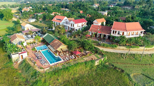 khu du lịch farmstay nhìn từ trên cao có nhiều công trình nhà ở, hồ bơi và cây cối