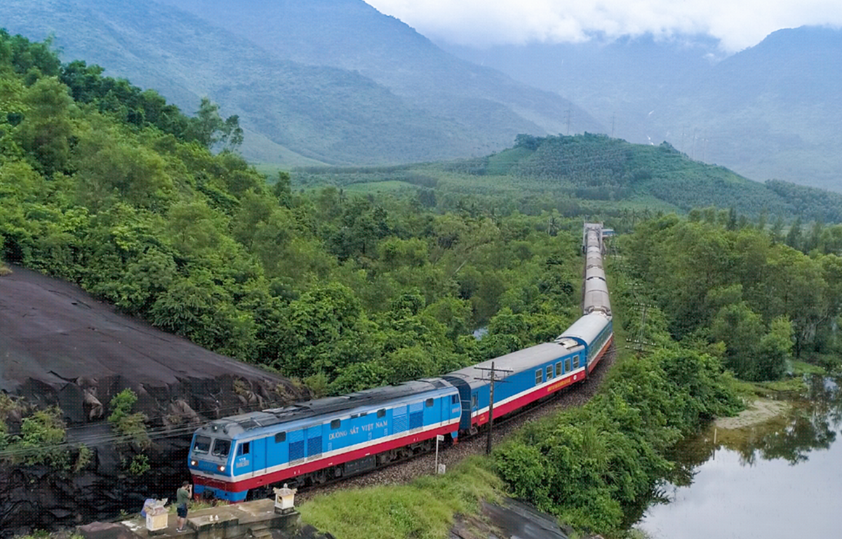 đoàn tàu đang chạy qua khu vực đồi núi có nhiều cây xanh